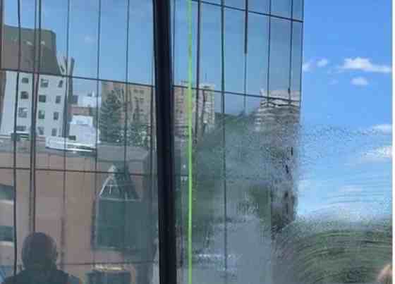 Before – high-rise office building glass panel with streaky residue